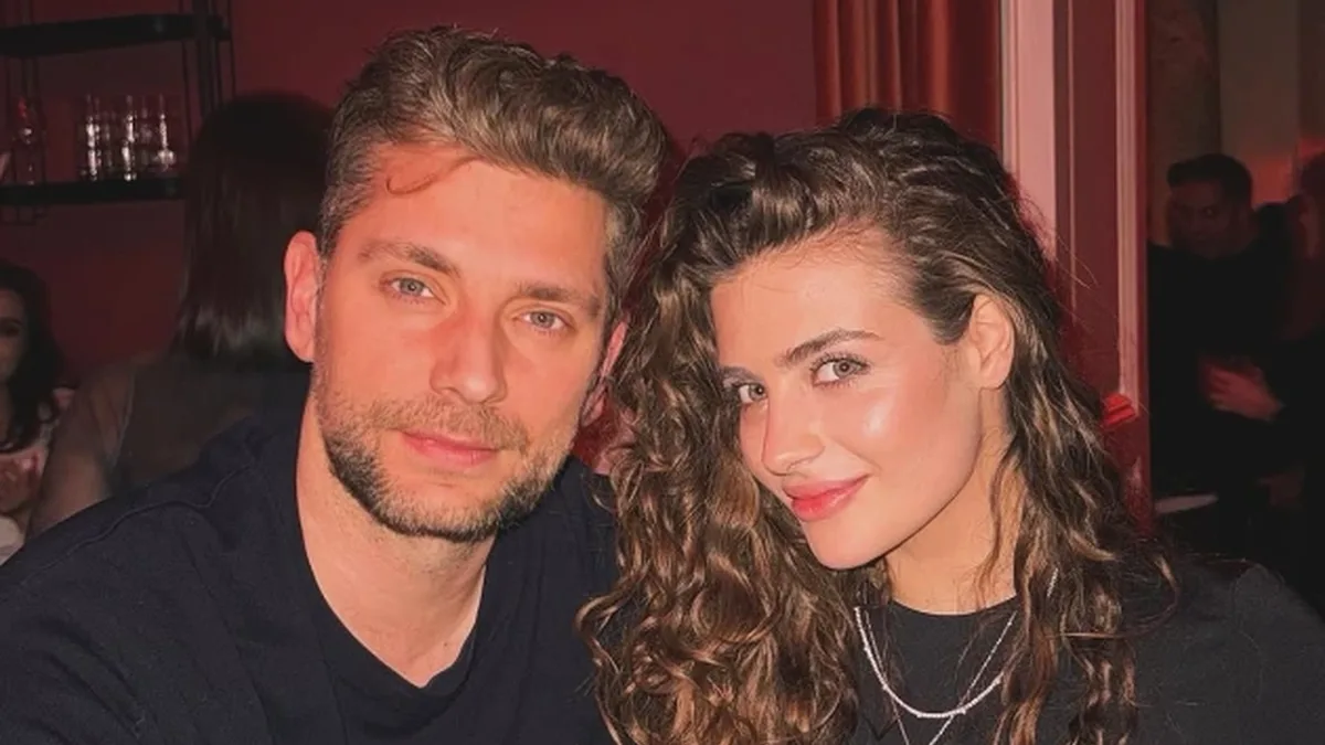 Ana Bodea și Valentin Butnaru, îmbrăcați în negru, stau apropiați într-un interior cu lumină caldă.