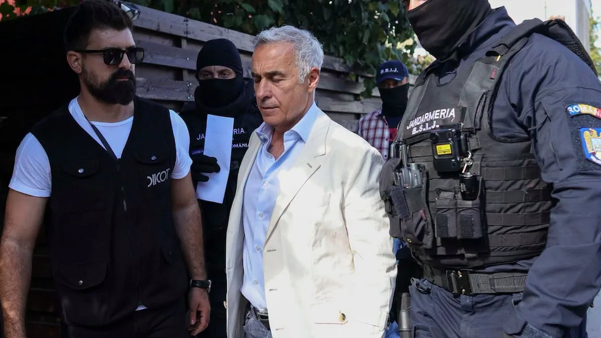 Călin Georgescu, în sacou deschis, între un bărbat cu vestă DIICOT și jandarmi cu fețele acoperite.