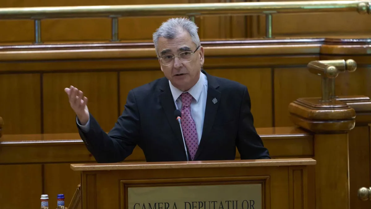 Petrișor Peiu vorbește la microfon de la tribuna Camerei Deputaților, cu o mână ridicată.