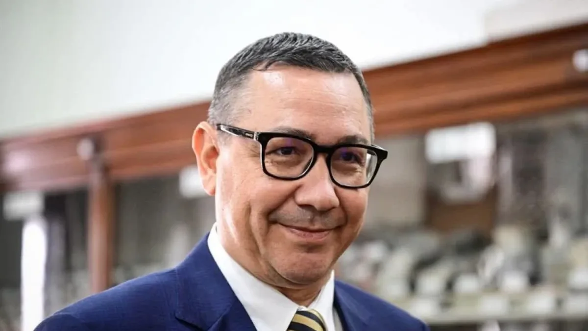 Victor Ponta, cu ochelari, costum albastru, cravată în dungi și insignă tricoloră, într-un interior cu vitrine.